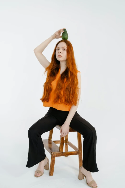 the woman sits on a stool with her hair blown