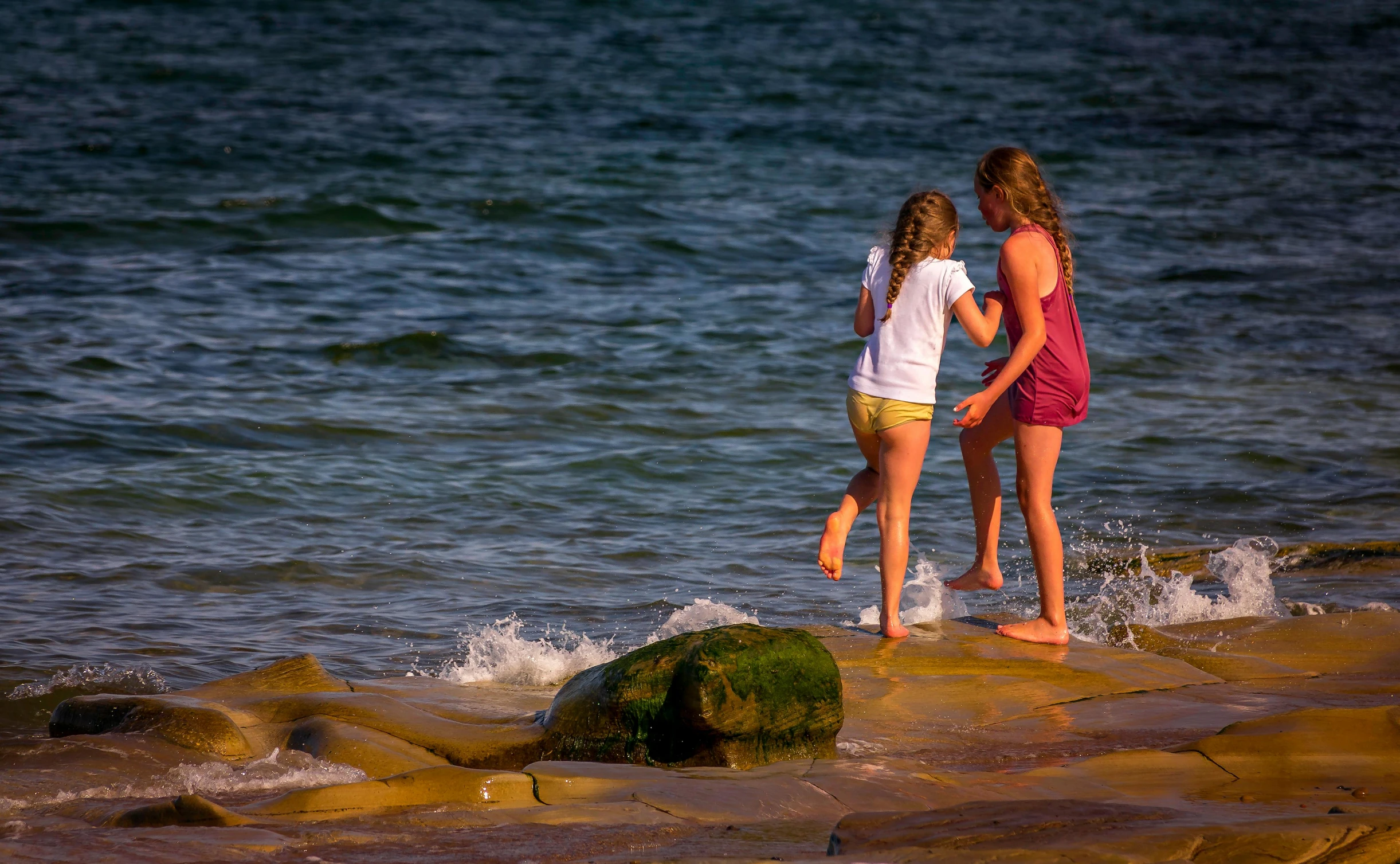 the girl is standing near a boy by the water