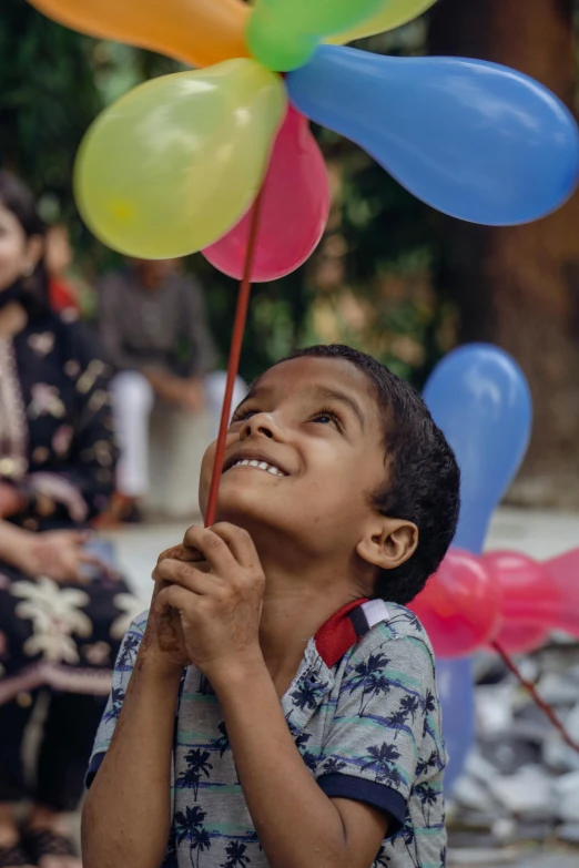 a boy holding balloons and smiling at someone