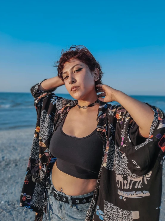 a woman wearing a black top and jeans on the beach