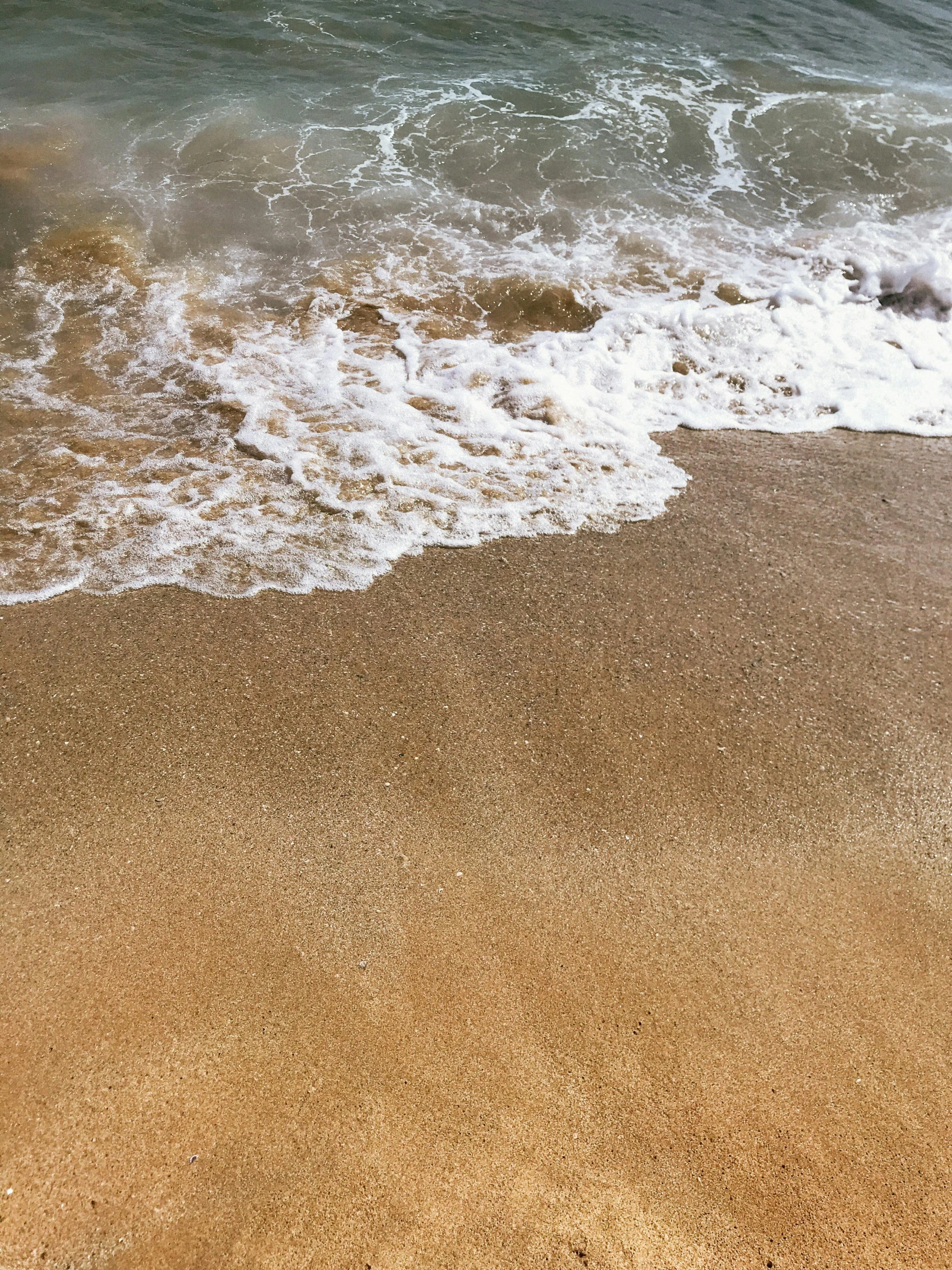 an orange piece of luggage lays in the sand on the beach