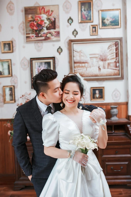 a bride and groom pose together in front of pictures on the wall