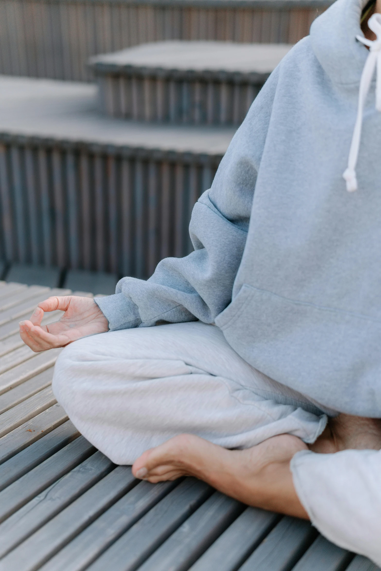 someone in a hoodie is sitting on a metal bench