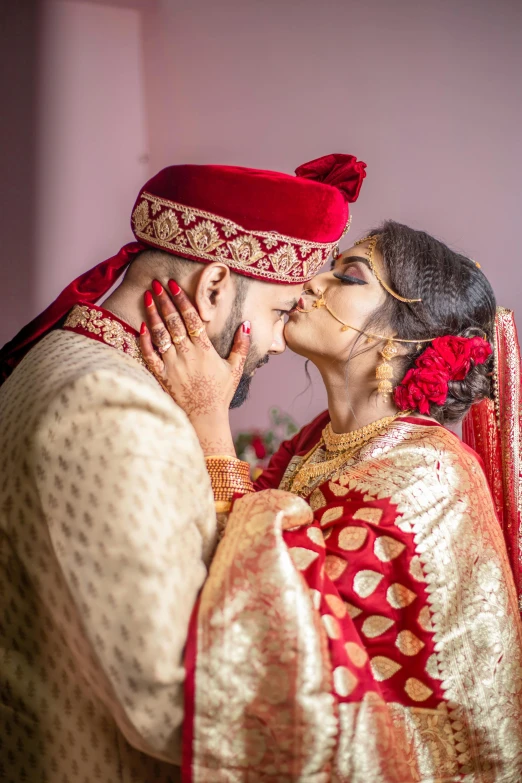 an indian couple is kissing in their traditional costume