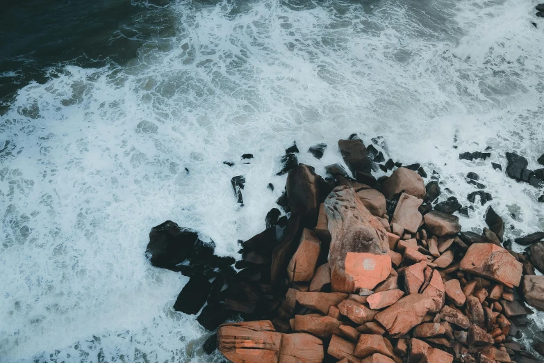 aerial po of rocky shoreline surrounded by foamy water