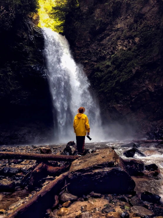 the man is standing in front of a waterfall