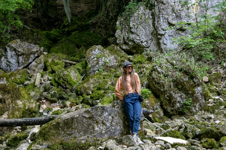 a man is posing by some rocks and trees