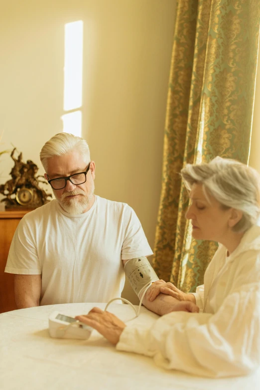 an older man and woman with a cast on their arms, who are sitting at a table with a cell phone