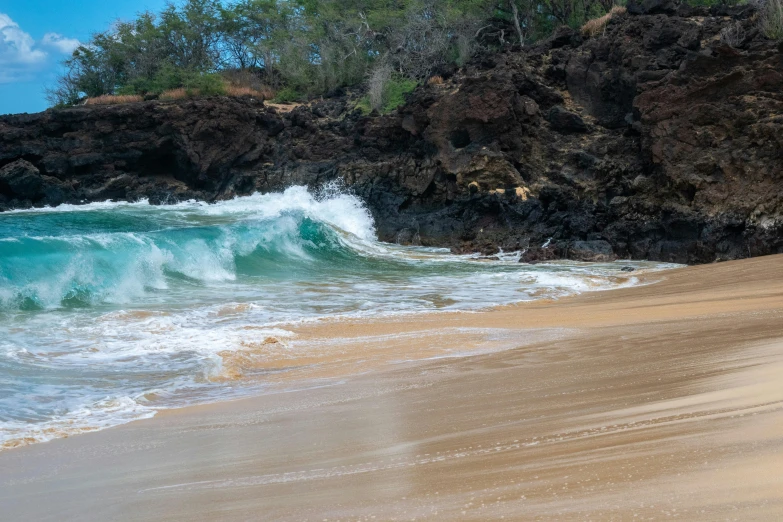 an ocean with waves hitting the rocks and sandy beach