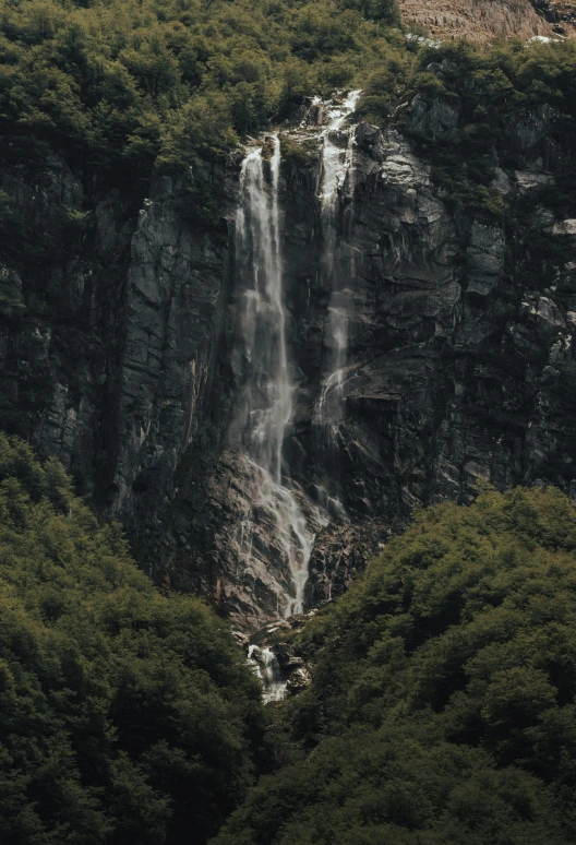 a large waterfall is shown over green trees