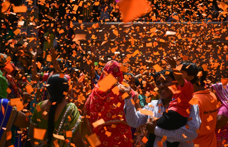 the confetti is in front of the people and the umbrellas are flying