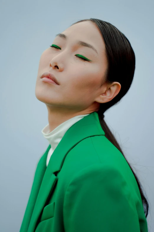 a woman wearing a green jacket and with bright green eyeshadow