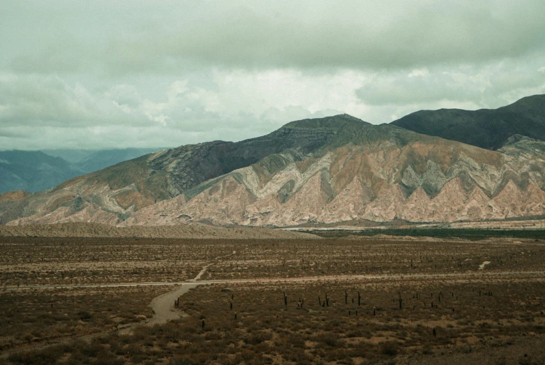 a long road leads into the mountains near a dirt field