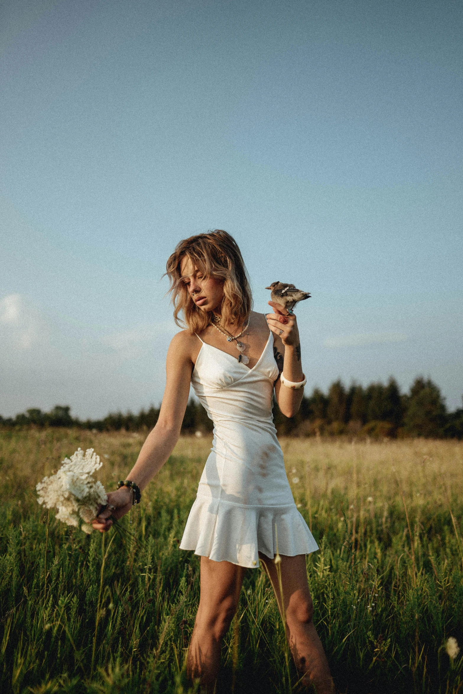 a beautiful woman in a white dress posing with her bird