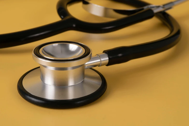 a medical stethoscope on yellow table with a black handle