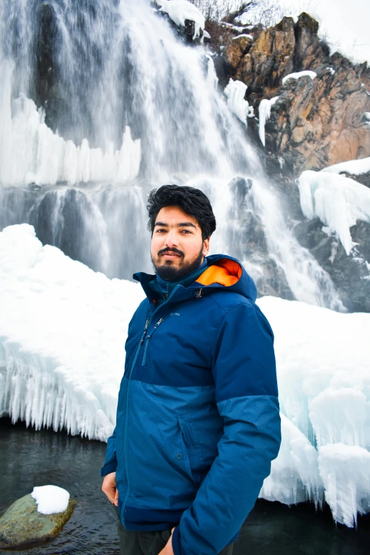 a man standing by a waterfall looking at the camera