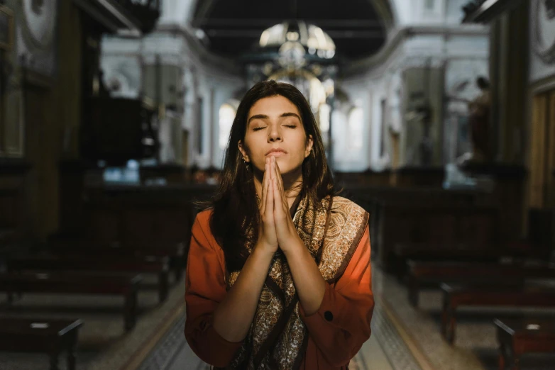 young woman with closed eyes praying inside a church