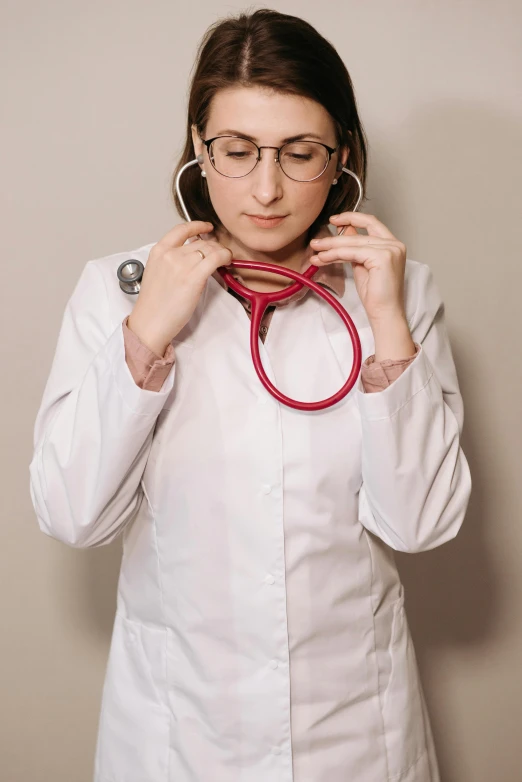 a woman wearing a white coat and holding up her red stethoscope