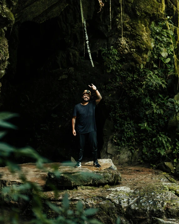 a man with a beard in front of a green rocky wall