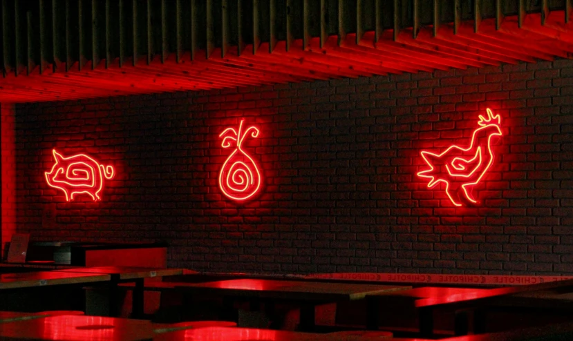several red neon signs on a brick wall