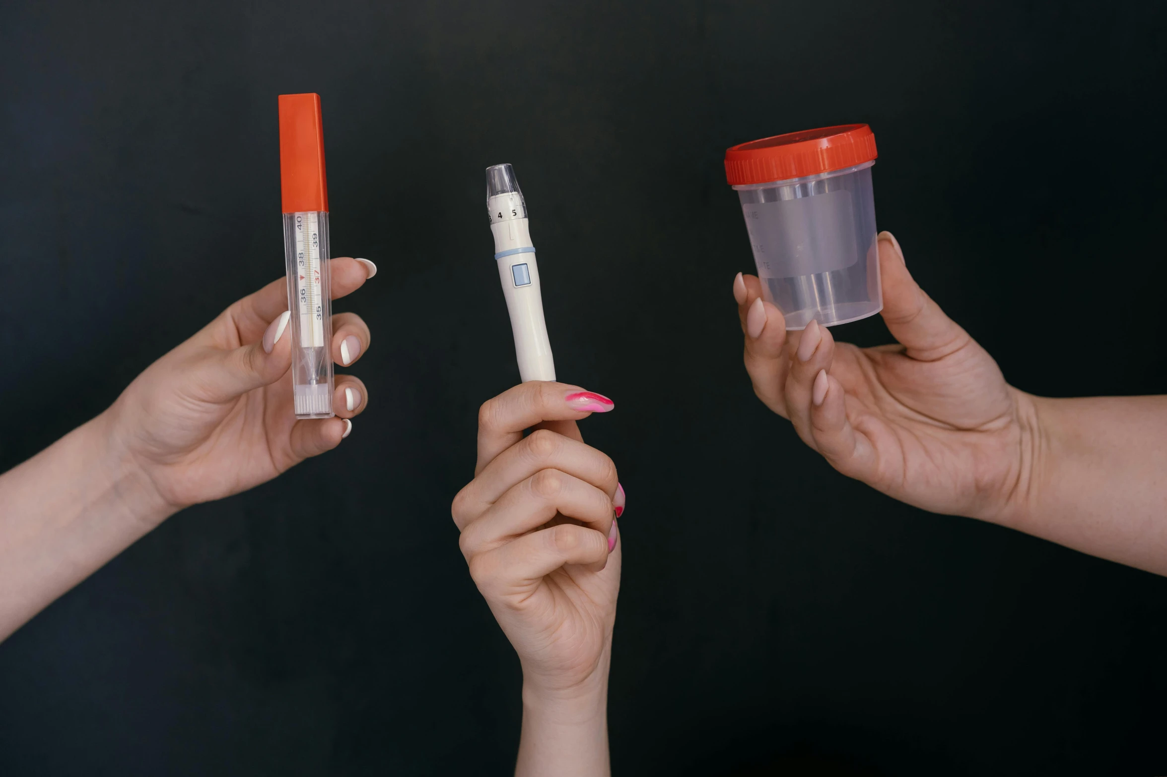 three hands hold up three different sized tubes with markers