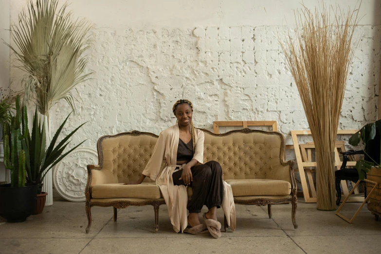 a person is sitting on a couch near some plants