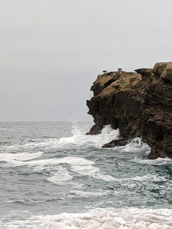 waves crashing onto a cliff face on a gloomy day