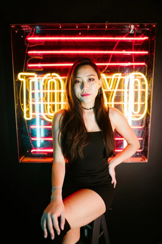 woman in black sitting by neon light signage