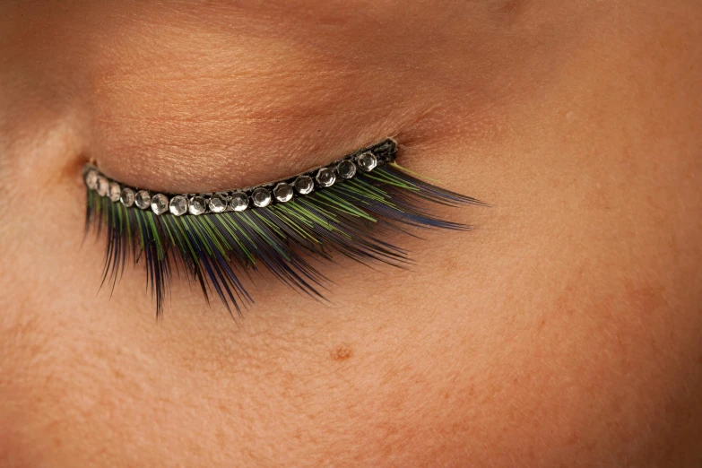 an open pair of eyelashes with green and black spiked eyelashes