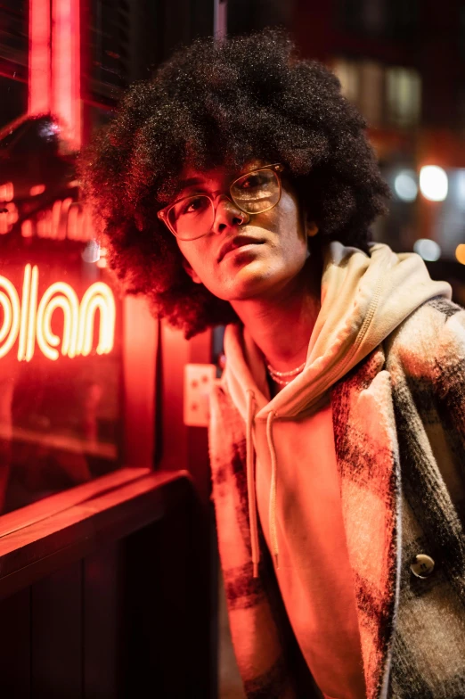 a man wearing glasses standing in front of a bar with red lights