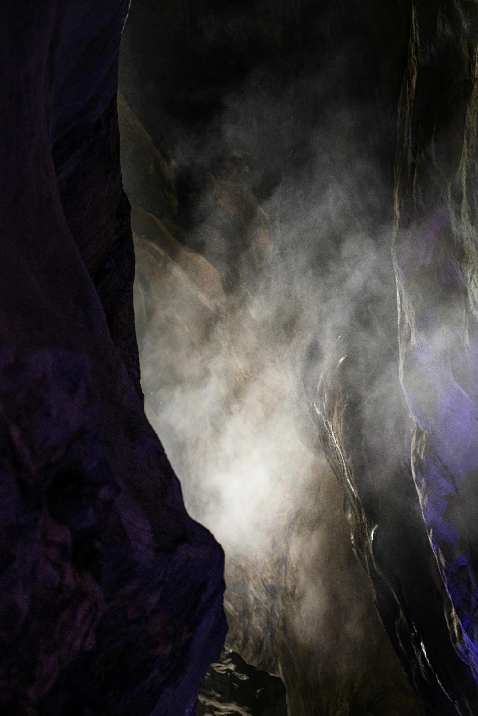 a very dark cave with some steam coming out of it