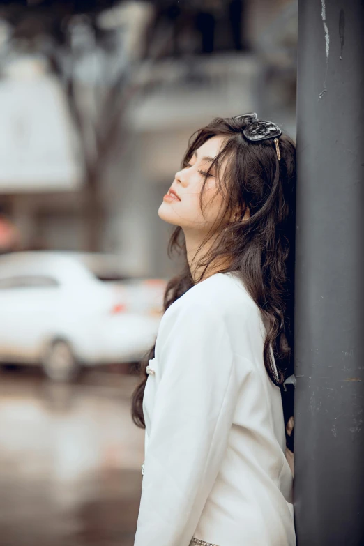 a young lady leaning up against a pole