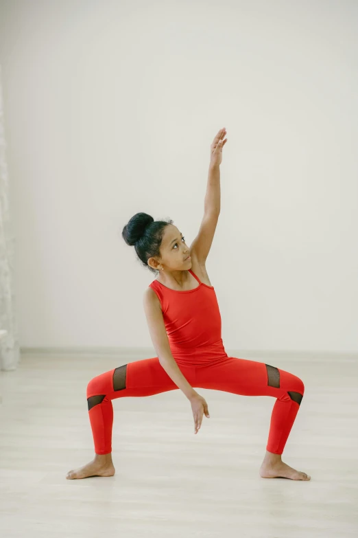 a woman in a red top is doing a yoga move