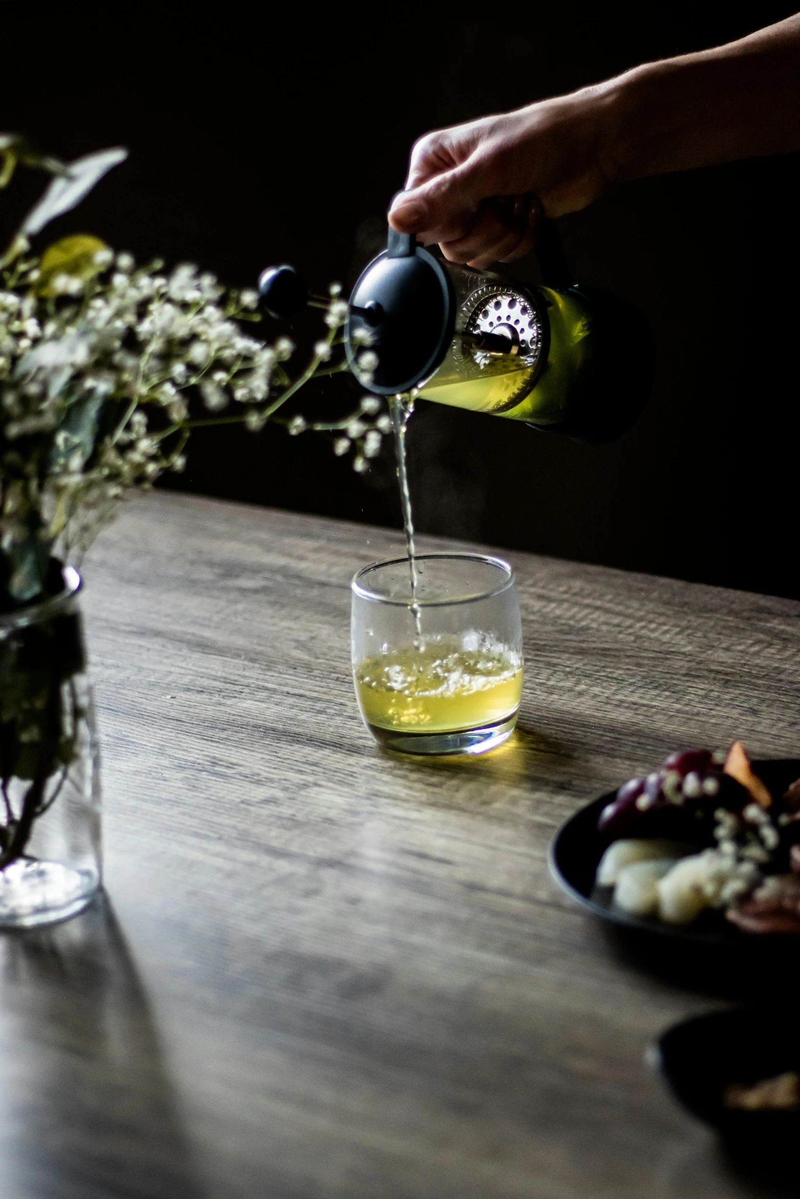 someone pouring syrup into a cup with flowers in the background