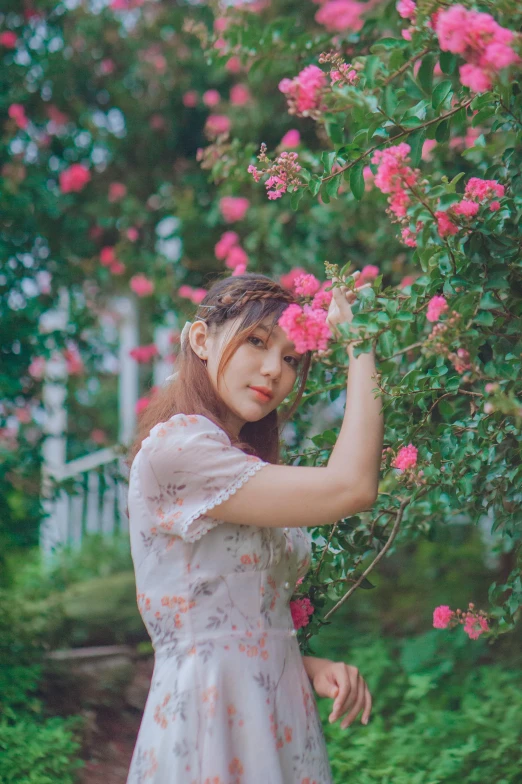 a young woman in white dress smelling pink roses