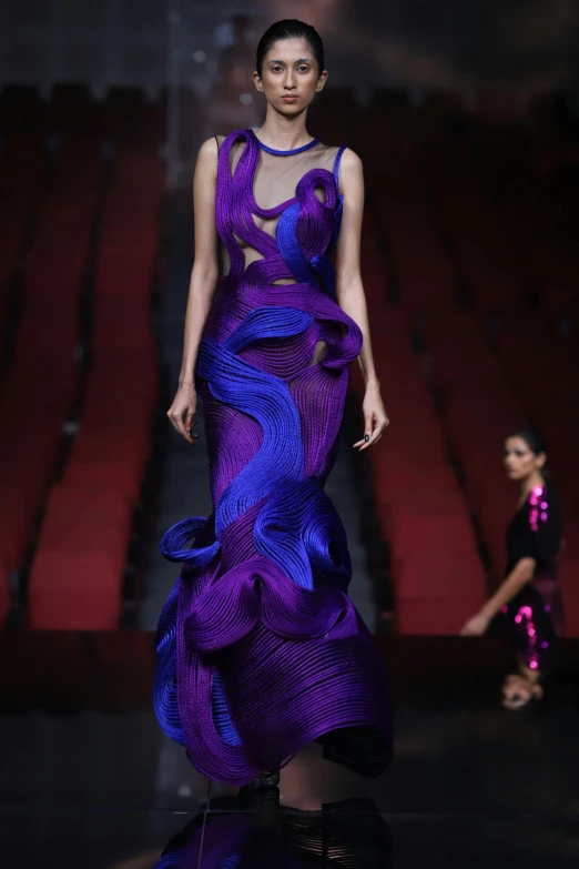 a model is walking down the runway wearing a purple dress