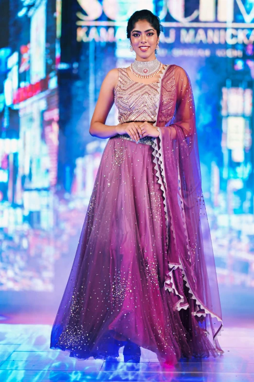 a young woman in a gown and accessories stands on the runway