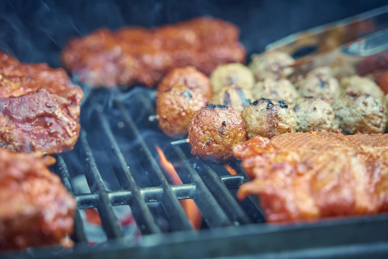 several meats being cooked on an outdoor grill