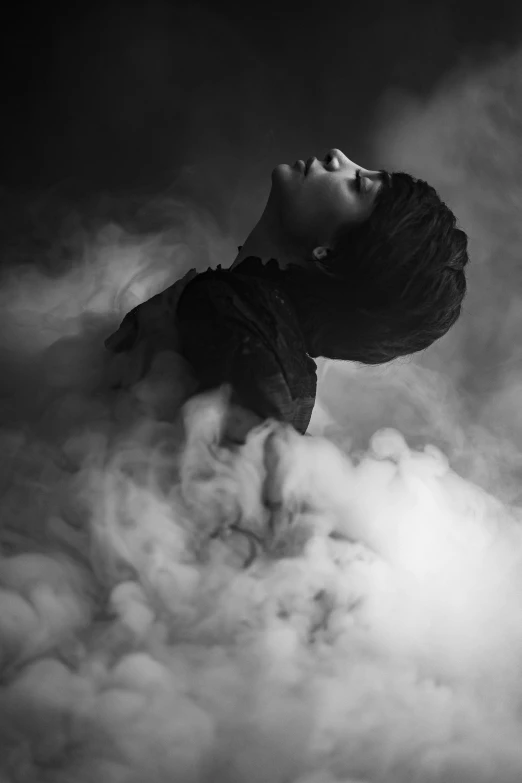 black and white pograph of woman standing above clouds