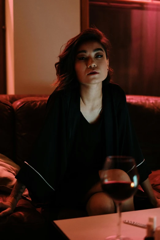 a woman sitting on a couch next to a wine glass