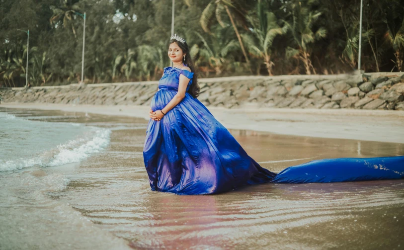 a woman wearing a purple and blue gown standing in the water