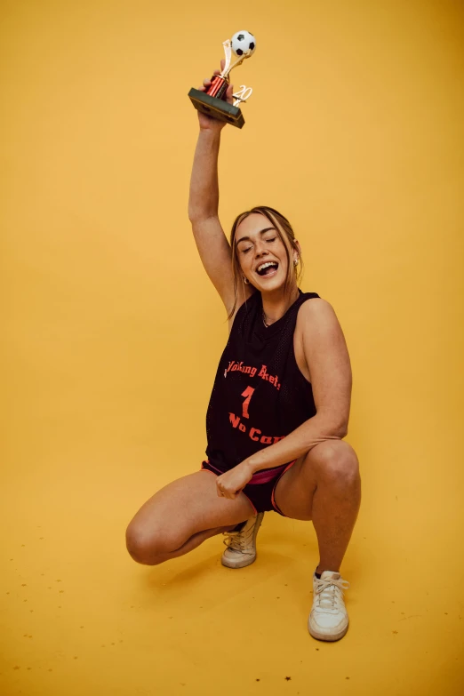 girl with trophy posing for a picture on yellow background