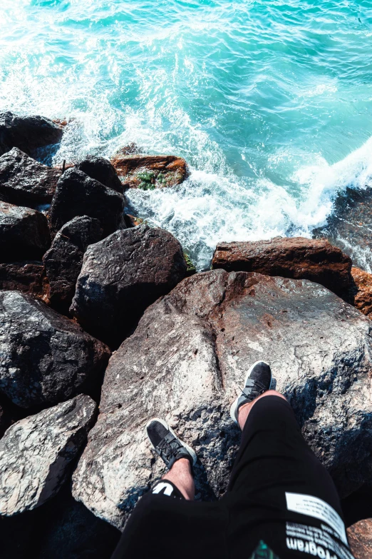 person sitting on rock cliff by the ocean