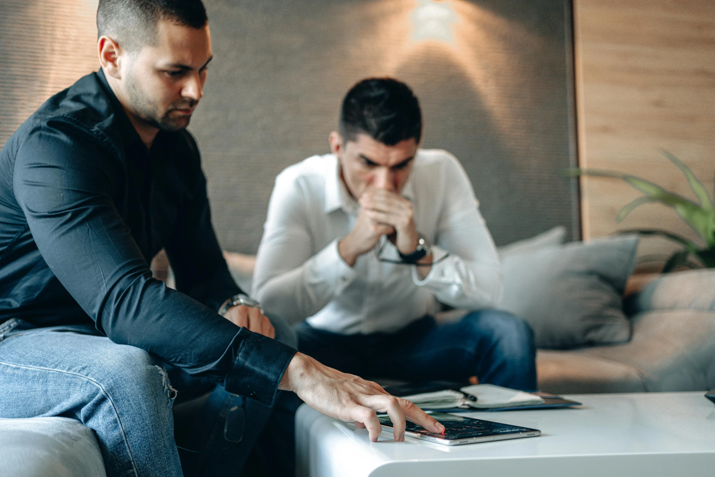 two men sitting down looking at a magazine