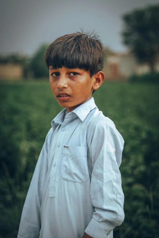 a boy stands in front of a field and stares ahead