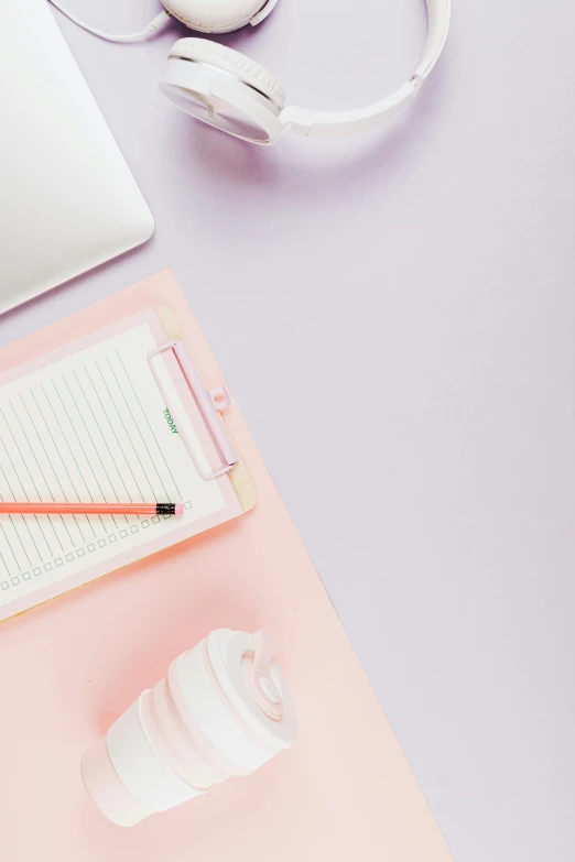 there is a coffee cup next to a notebook and headphones