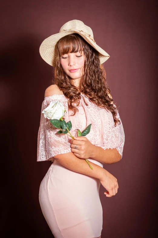 a woman wearing a dress and a hat holding a rose