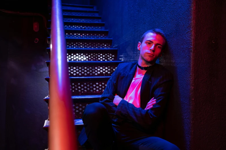 a man sitting in front of a stairway next to a blue wall