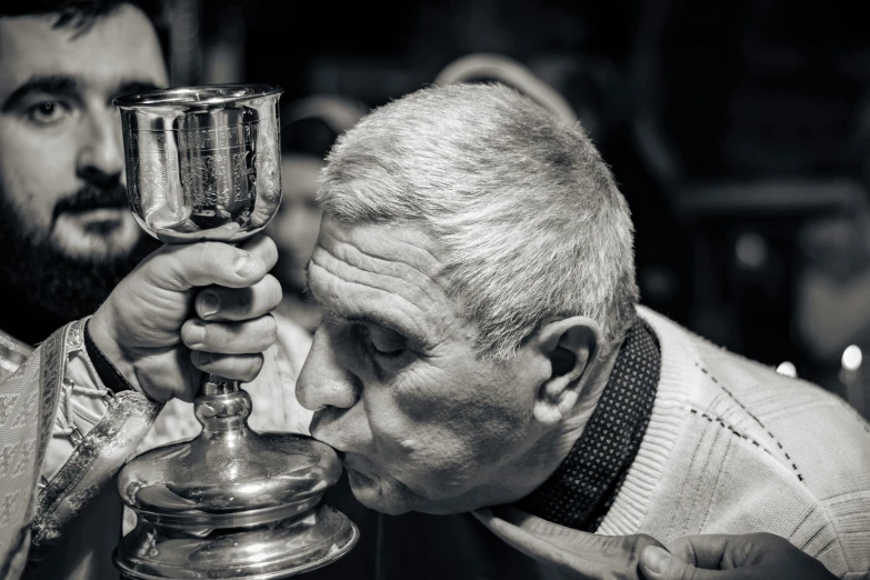 a priest holding up a lit candle while a man looks at it