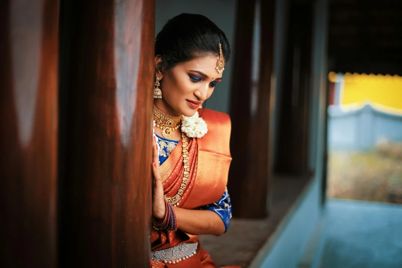 a woman with an orange sari is looking through the wall